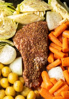 an assortment of vegetables including carrots, potatoes and meat on a platter with seasoning