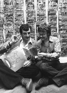 two men sitting on the floor reading books