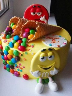 a yellow cake with gummy bears and an ice cream cone in the shape of a smiley face