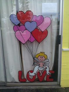 a window decorated with hearts and a cupid holding a bunch of heart shaped balloons