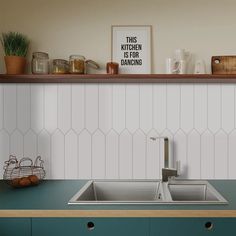 a kitchen with green counter tops and white tile backsplash, wooden shelves above the sink