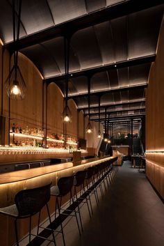 a dimly lit bar with several chairs and lights on the wall, along with stools