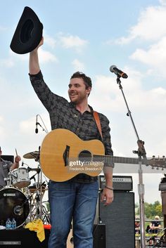 a man is holding up his guitar and singing