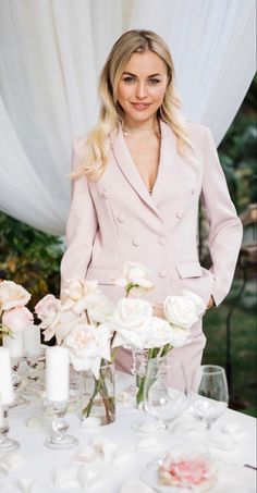 a woman standing next to a table with flowers and candles