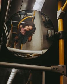 a reflection of a woman in a mirror on the side of a yellow rail car