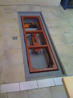 a floor drain in the middle of a tiled floor with an orange window on it