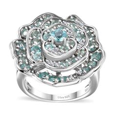 a white gold ring with blue and white diamonds in the center, surrounded by an intricate flower design