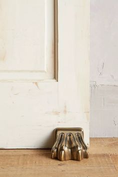 a pair of metal feet sitting on top of a wooden floor next to a white door