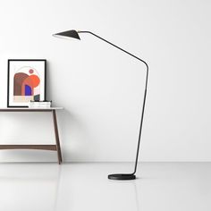 a black floor lamp sitting next to a white table with a framed photograph on it