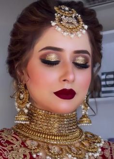 a woman with red lipstick and gold jewelry