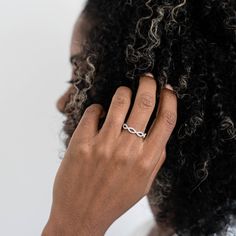 a close up of a person's hand with a ring on her finger and curly hair