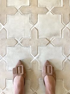 a person standing on a tile floor with their feet up in the air and wearing sandals