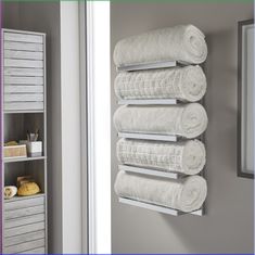 towels are hanging on the wall next to a towel rack and shelves in a bathroom