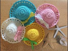 four crocheted hats sitting on top of a sandy beach next to a starfish