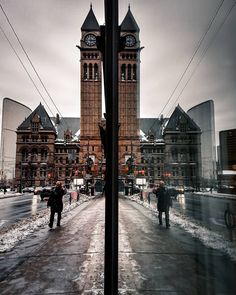 two people walking down the street in front of a clock tower