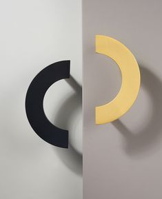 two black and yellow circular objects are on the wall next to each other, one is shaped like a crescent