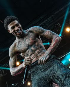 a man with tattoos holding a microphone on stage