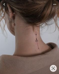 a woman's neck with a small flower tattoo on the back of her neck