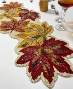 the table is set with two wine glasses and three decorative placemats, all decorated in autumn colors