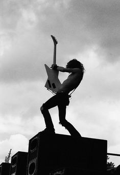 black and white photograph of a man playing an electric guitar on top of a building