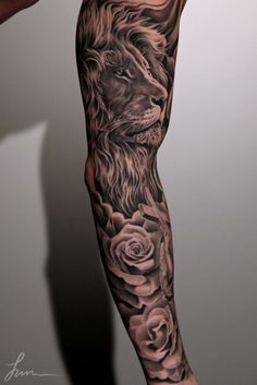 a man's leg with a lion and roses tattoo design on it, in black and grey