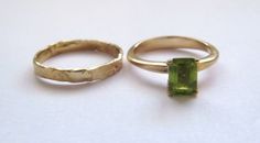 "Stunning set of 2 14K yellow gold stacking rings - a peridot solitaire ring and a unique wedding band. This set consists of 2 beautiful solid gold rings: The 1st is a rustic wedding band, with an uneven design that gives it a distinctive \"handmade\" look. It is forever changing, never looking the same. The 2nd ring has a sparkling green rectangular peridot set in a beautiful base. This can be an awesome engagement ring. This modern bridal ring set is perfect for a boho bride. The rings have a Yellow Gold Peridot Jewelry With Emerald Cut, Yellow Gold Peridot Stackable Rings For Wedding, Green 14k Gold Stackable Wedding Rings, Green Bezel Setting Stackable Rings For Wedding, Yellow Gold Peridot Stackable Rings For Anniversary, Stackable Yellow Gold Peridot Jewelry, Yellow Gold Stackable Rings With Peridot, Green Stackable Sapphire Ring For Wedding, Wedding Stackable Peridot Rings