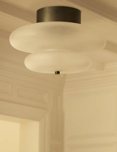 a light that is hanging from the ceiling in a room with white walls and flooring