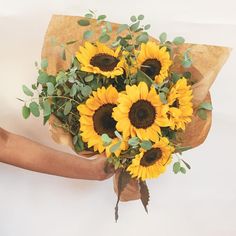 a person holding a bouquet of sunflowers in their hands