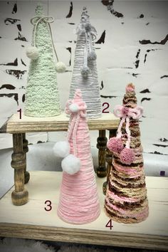 three knitted christmas trees sitting on top of a wooden table