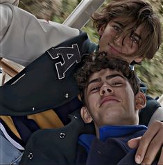 two young men sitting next to each other in a car, one with his eyes closed