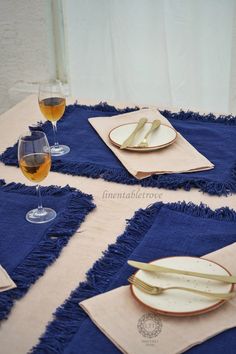 the table is set with place mats, plates and wine glasses on it for two people to enjoy