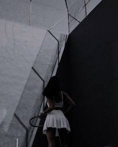 a woman holding a tennis racquet standing next to a wall