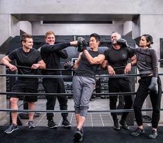 five people in black shirts are standing on a metal railing and posing for the camera