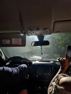 two people are sitting in the back seat of a car and one person is using a cell phone