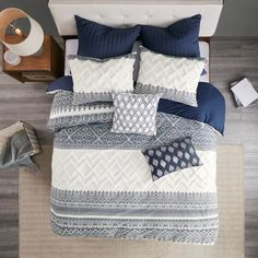 an overhead view of a bed with blue and white comforters, pillows and blankets