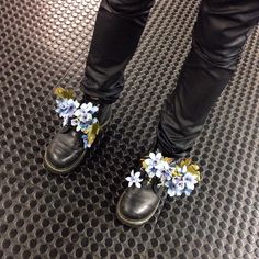 a pair of black shoes with blue flowers on them are standing on a metal surface