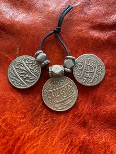 "This is a lovely set of antique silver coin pendants from Rajasthan, India. Each pendant measures ~ 1 7/16\" (3,6 cm) long by ~ 1 1/8\" (2,85 cm) wide. The pendants feature old, double-sided Moghul coins with cornerless cube top bails. These pieces have absolutely wonderful patina and wear and are a fairly well-matched set. They weigh 47.2 grams including the string they are on." Traditional Engraved Round Coin Necklace, Antique Coin Pendant Necklace For Festivals, Traditional Silver Coin Necklace, Traditional Silver Coin Necklaces, Traditional Silver Coin Necklace With Round Pendant, Traditional Coin Pendant Necklace For Festivals, Traditional Handmade Coin Necklace, Handmade Traditional Coin Necklace, Traditional Engraved Medallion Coin Necklace