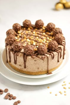 a cake with chocolate frosting and nuts on top sitting on a white platter