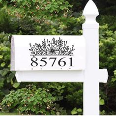 a white mailbox sitting in front of a tree and bushes with the number 851 on it