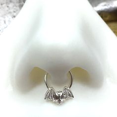 "Bat Septum Ring, Septum Hoop, Bat Nose Ring, Sterling Silver Nose Ring, Tiny Bat Septum Piercing, Septum Hoop, Bat Jewelry, Goth, Punk, Edgy WHAT IT IS AND WHY YOU WANT IT: The little bat on this septum ring is adorable AND a little spooky! The perfect combo! It is hand molded using fine silver in a mold I personally made just for this process. Then it is soldered to a solid sterling silver hoop. Choose the gauge and diameter you prefer. Solid gold option will be a 22k solid gold bat on a solid Bat Septum Piercing, Bat Nose Ring, Bat Nose, Cute Septum Rings, Septum Piercing Jewelry, Sterling Silver Nose Rings, Septum Hoop, Bat Jewelry, Types Of Ear Piercings