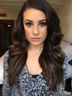 a woman with long brown hair wearing a black and white top is looking at the camera