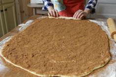 a person in an apron making food on top of a table next to a rolling pin