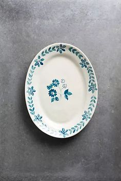 a blue and white plate sitting on top of a cement floor next to a wall