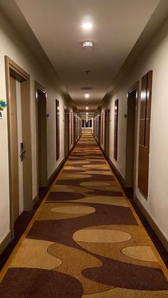 a long hallway with brown and tan carpeting on both sides leading to two doors