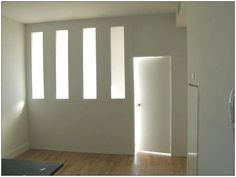 an empty room with white walls and wooden floors is seen from the doorway to the hallway