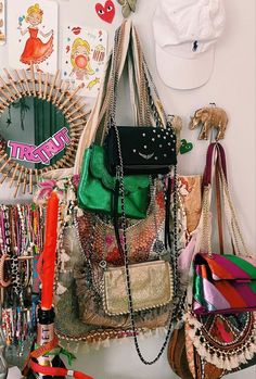 many purses are hanging on the wall with other items in front of them,