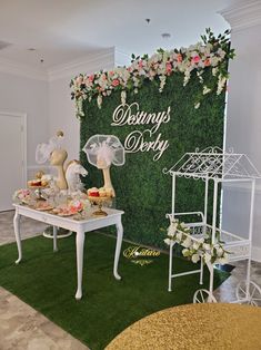 a table topped with cakes and pastries next to a wall covered in greenery