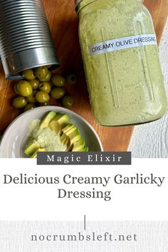 a jar of creamy garlicky dressing next to some olives on a cutting board