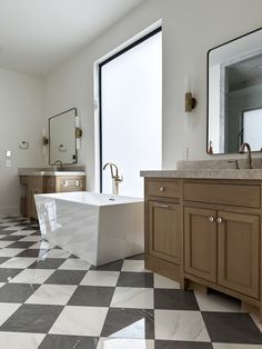 a bathroom with a checkered floor and large bathtub next to two double sinks