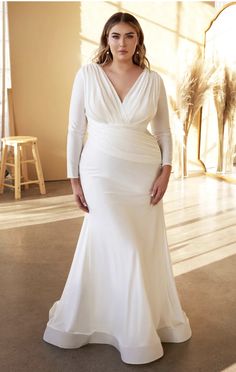 a woman in a white wedding dress posing for a photo with her hands on her hips